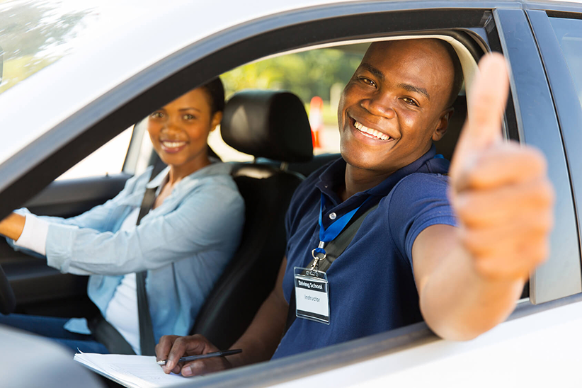 A person learning to drive with an instructor in a car.